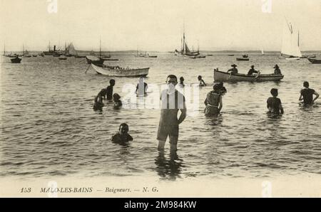 Un homme en maillot de bain se dresse sur les vagues de la plage de Malo-les-bains, près de Dunkerque en France. Derrière lui se trouvent d'autres baigneurs ainsi que divers bateaux. Banque D'Images