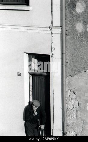 Homme allumant une cigarette du matin dans une rue française. Banque D'Images