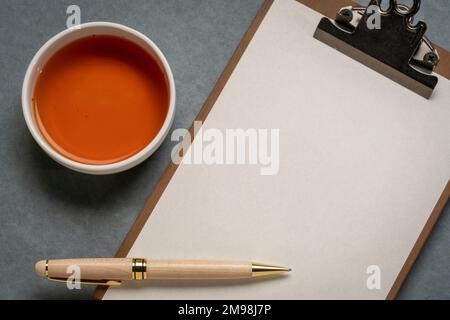 presse-papiers avec papier vierge, bureau plat avec une tasse de thé et un stylo élégant Banque D'Images