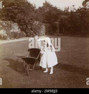 Petite fille (Violet Auerbach) avec une brouette dans le jardin arrière de sa maison au 1 Carlton Road, Ealing, West London. Banque D'Images