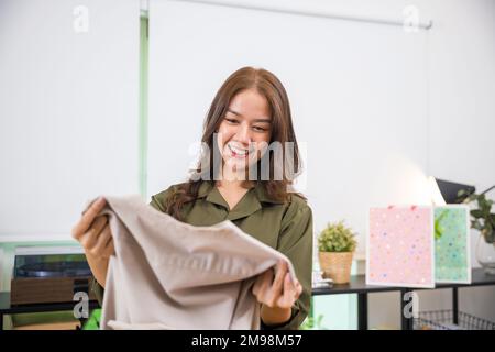 femme ouvrant le paquet de sac de shopping après avoir commandé de nouveaux vêtements de mode à la maison Banque D'Images