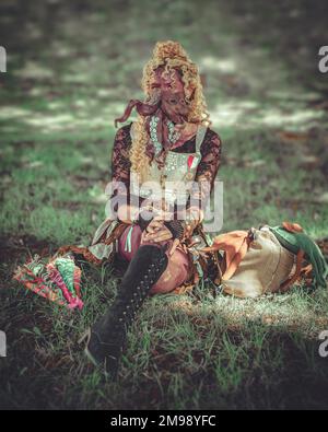 Une étrange apparence femelle steampunk assis sur l'herbe, elle a un pieuvre attaché à son visage. Banque D'Images