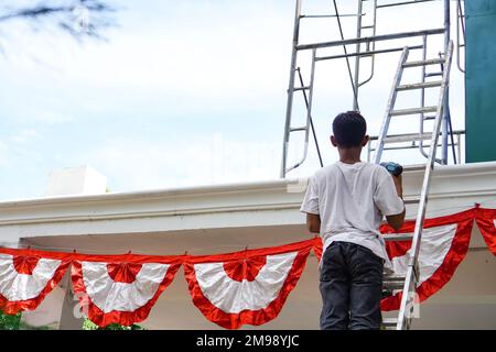 Mise en place d'une décoration de chaîne de drapeaux sur le toit du bâtiment pour le jour de l'indépendance Banque D'Images