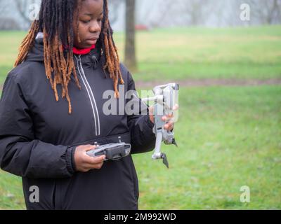 Jeune adolescent afro-américain enjoué portant des vêtements de sport vérifiant voler un drone d'appareil photo dans un parc avant utilisation. Banque D'Images