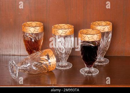 Boisson, ensemble de cinq gobelets en verre à bordure dorée; photo sur fond en bois. Banque D'Images