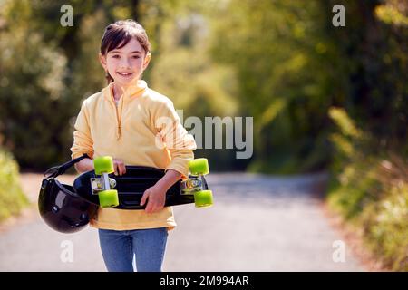 Portrait de fille avec skateboard marchant le long de Country Road Banque D'Images
