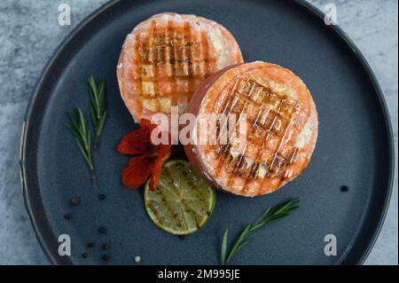 Rouleau de saumon grillé avec mozzarella. Décoration avec vert citron vert et fleurs comestibles Banque D'Images