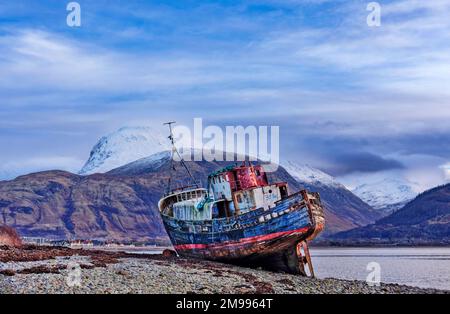 Vieux bateau de Caol fort William Scotland bateau reposant sur la plage et la neige au-dessus de la chaîne de montagnes de Nevis Banque D'Images