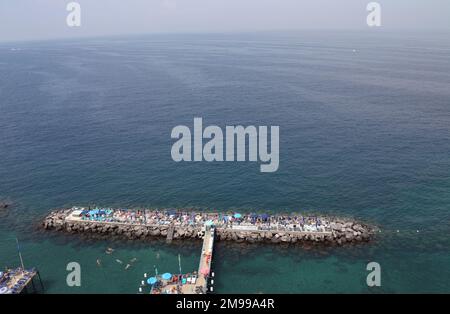 Baigneurs de soleil se détendant et nageant au bord de la jetée du club de plage de Sorrente, Campanie, Italie Banque D'Images
