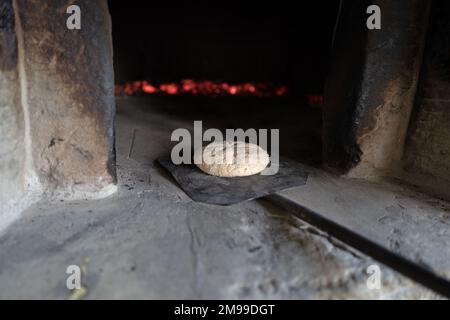 Le pain fait maison entre dans un four traditionnel en bois d'une maison de campagne de Toscane Banque D'Images