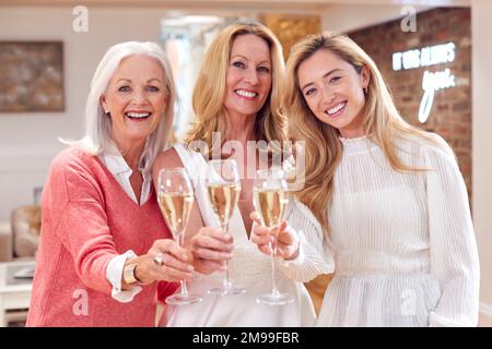 Portrait d'une grand-mère avec une fille adulte et une petite-fille essayant de s'habiller avec une robe de mariage dans le magasin Banque D'Images