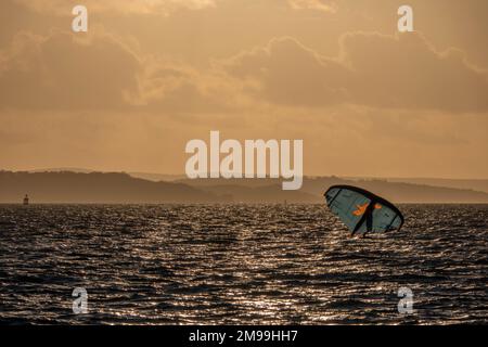 Planche à voile à Hill Head Hampshire Angleterre avec l'île de Wight et une brume orange du soleil se coucher en arrière-plan Banque D'Images