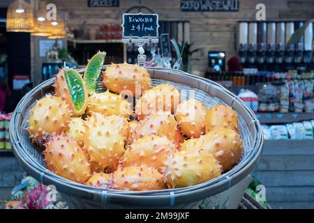 Un stand de marché de kiwano orange ou de melons cornés, Cucumis metaliferus. Le fruit exotique est à vendre, clairement marqué et le prix Banque D'Images