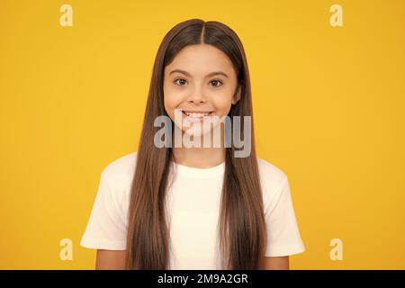 Joyeux portrait d'adolescent. Portrait d'une petite fille positive mignonne isolée sur fond jaune. Enfant caucasien attrayant souriant et regardant l'appareil photo Banque D'Images