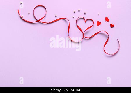 Ruban rouge avec coeurs et perles sur fond lilas. Célébration de la Saint-Valentin Banque D'Images