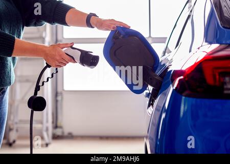 Gros plan de la main fixant le câble de chargement à une voiture électrique écologique sans émission Banque D'Images