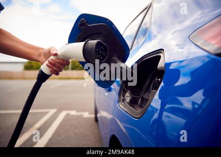 Gros plan de la main fixant le câble de chargement à une voiture électrique écologique sans émission Banque D'Images