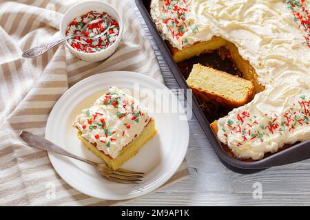 Tranche de gâteau de feuille de vanille avec glaçage à la crème fouettée, garni de saupoudrés du nouvel an sur une pelle à gâteau sur une assiette blanche, vue en grand angle Banque D'Images