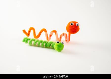 nettoyant pour tuyaux à pompons aux yeux googly orange wrigly ver vert caterpillar drôle personnage pudles jouet fait main isolée sur un fond blanc Banque D'Images