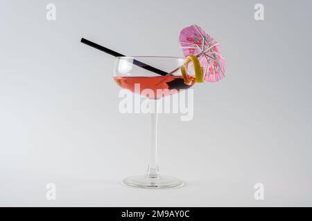 Coupe de champagne avec cocktail pina colada rose, parapluie citron et paille noire isolée sur fond blanc Banque D'Images