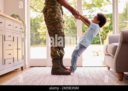 Gros plan du Père de l'Armée aimant dans la maison uniforme sur le congé avec son debout sur les pieds Banque D'Images