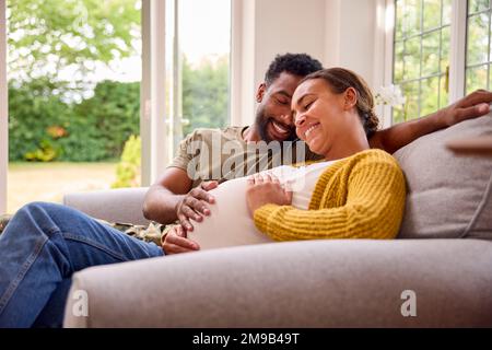 Couple enceinte avec une femme assise à côté du mari de l'Armée de terre dans la maison uniforme en congé Banque D'Images