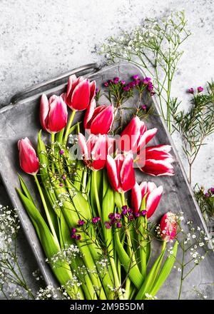 Vue de dessus de belles tulipes roses et blanches, de gitsophila et de fleurs de cire pourpres sur un ancien plateau en métal Arrangement floristique de printemps pour la décoration de maison. Banque D'Images