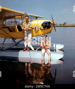 Piper J3-65 Cub float-plane, avec le père et le fils pêchant à partir d'un float. Banque D'Images