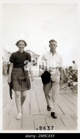 Cliftonville, Margate, Kent - Un jeune couple intelligent se baladant le long de la promenade en bord de mer par une chaude journée d'été. Banque D'Images