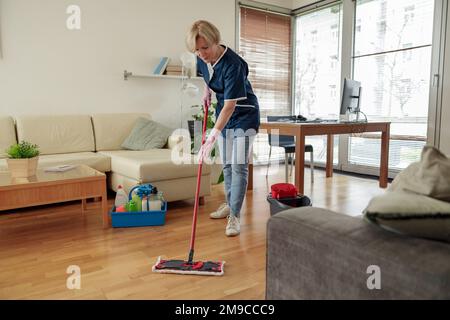 Articles de maison professionnels sur un plancher de lavage uniforme avec une vadrouille dans le salon Banque D'Images