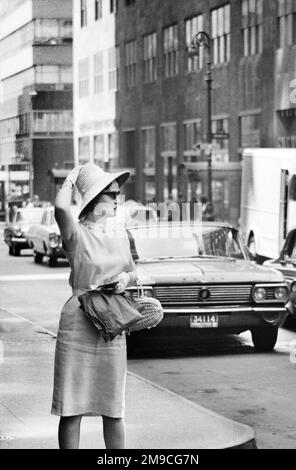 Woman on Street Corner Holding Hat on Head, New York City, New York, USA, Angelo Rizzuto, Collection Anthony Angel, juin 1964 Banque D'Images