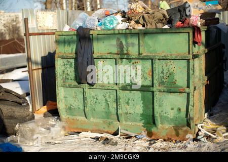 Vidage en ville. Grand conteneur à ordures vert. Beaucoup de déchets. Banque D'Images