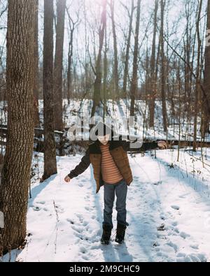 Enfant marchant sur un sentier de randonnée enneigé en hiver dans la forêt Banque D'Images