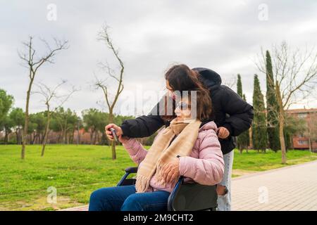 une fille prenant des photos avec sa grand-mère dans un fauteuil roulant Banque D'Images