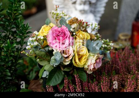roses pastel décolorées sur une tombe devant un ange sur fond flou Banque D'Images