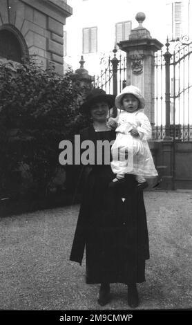 Une petite fille en blanc est tenue par une femme en noir Banque D'Images