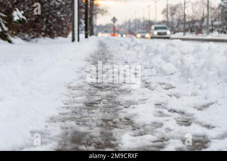 Route d'hiver avec fonte de neige salée. Gros plan du trottoir avec de la neige fondante le jour de la neige. Mise au point sélective Banque D'Images