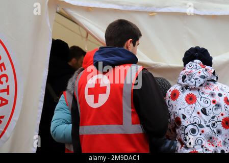 Dnipro Ukraine 2023-01-14. Les volontaires de la Croix-Rouge aident les blessés près d'une maison détruite après une attaque de missiles russes. Badge rouge sur l'uniforme de paramedi Banque D'Images