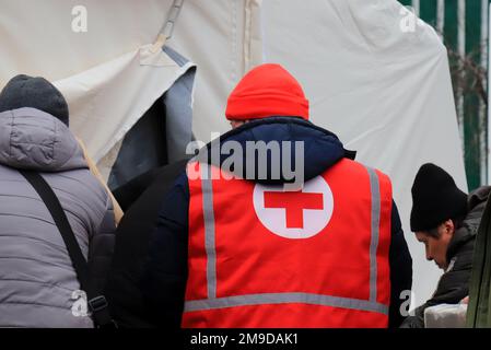 Dnipro Ukraine 2023-01-14. Les volontaires de la Croix-Rouge aident les blessés près d'une maison détruite après une attaque de missiles russes. Signe de croix rouge sur l'uniforme d'ambulancier Banque D'Images