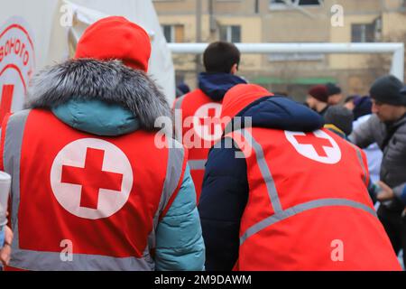 Dnipro Ukraine 2023-01-14. Les volontaires de la Croix-Rouge aident les blessés près d'une maison détruite après une attaque de missiles russes. Signe de croix rouge sur l'uniforme d'ambulancier Banque D'Images