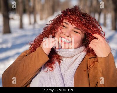 Portrait d'une femme souriante aux cheveux rouges lors d'une promenade en hiver. Banque D'Images
