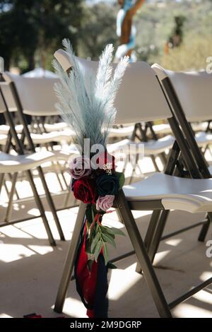 Boho sombre décoration de réception de mariage - roses rouges, pourpres avec plumes de sarcelle des ornements floraux Banque D'Images