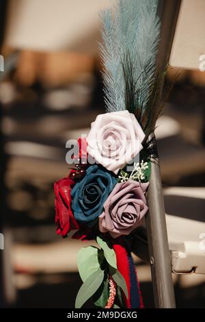 Boho sombre décoration de réception de mariage - roses rouges, pourpres avec plumes de sarcelle des ornements floraux Banque D'Images