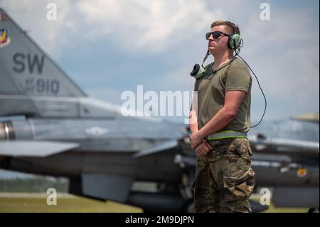 ÉTATS-UNIS Air Force Airman classe 1st Leo Johansson, chef d'équipage de l'escadron de maintenance de l'aéronef 142nd, base de la Garde nationale aérienne de Portland, Oregon, attend le lancement d'un aigle F-15C tandis qu'un faucon de combat F-16C affecté à la base aérienne de Shaw en Caroline du Sud, taxis dans le cadre du programme d'évaluation du système d'armes-est 22,08 à Tyndall AFB, Floride, 17 mai 2022. Le WSEP est un exercice d’évaluation officiel de deux semaines conçu pour mettre à l’essai les capacités d’un escadron à conduire des systèmes d’armes à feu vivant pendant des missions d’entraînement de combat aérien à aérien. Banque D'Images