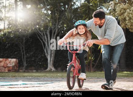 Vous y êtes presque. un homme qui aide sa fille tout en faisant un vélo. Banque D'Images