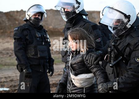 Erkelenz, Allemagne. 17th janvier 2023. Des policiers dirigent la militante suédoise pour le climat Greta Thunberg (M) hors d'un groupe de manifestants et d'activistes et loin du bord de la mine de lignite à fosse ouverte Garzweiler II et la détendent. Des militants et des opposants au charbon poursuivent mardi leurs manifestations dans plusieurs endroits de la Rhénanie-du-Nord-Westphalie. Credit: Federico Gambarini/dpa/Alay Live News Banque D'Images