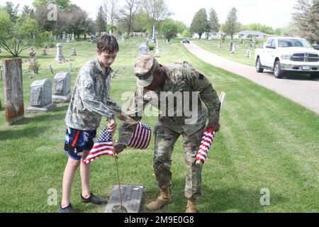 ÉTATS-UNIS Le Sgt. Gregory Betty du Commandement de la Réserve de l'Armée de terre, le Sgt. Maj. De la Division de préparation de 88th, et Isiah Hyma placent un drapeau américain à la tombe d'un ancien combattant américain au cimetière Woodlawn. Le cimetière a été l'arrêt final pour le Ruck pour la marche de Ruck de 5 kilomètres à Sparta Wis, 18 mai 2022. Banque D'Images