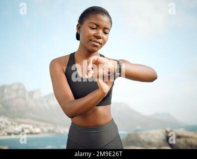 Définissez vos objectifs et poursuivez-les. une jeune femme prenant une pause pendant une course pour vérifier sa montre. Banque D'Images