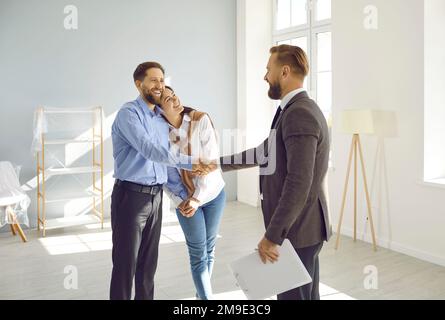 Ariendly realtor milite les mains avec un jeune couple marié qui vient d'acheter cette maison. Banque D'Images