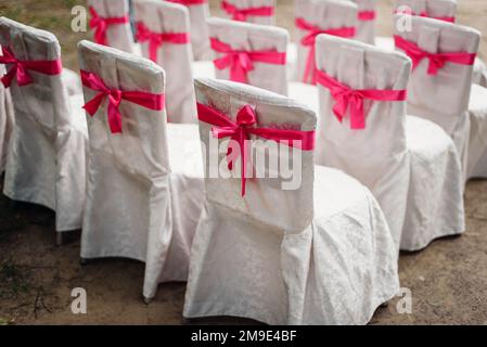 chaises blanches décorées de rubans roses pour la cérémonie de mariage Banque D'Images